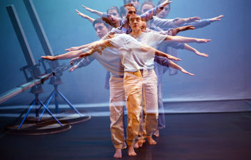 Dansare står på rad framför varandra med armarna utsträckta.