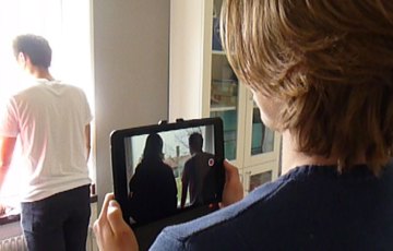 En elev filmar med ipad en annan elev, sett över axeln på filmaren.
