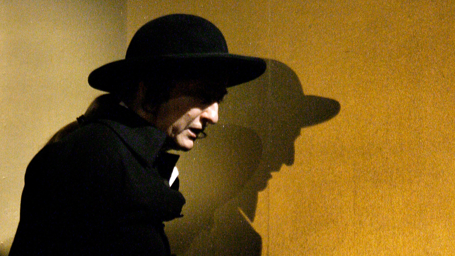 en person i svart hatt och rock i profil.