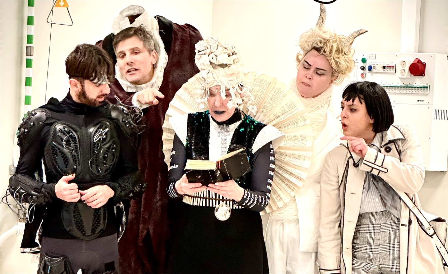  Fem karaktärer, en deckare en huvudlös man med huvudet i famnen, en svartklädd superhjälte, en magiker med fantasykläder, en gud med vit kostym, hårigt bröst och horn.