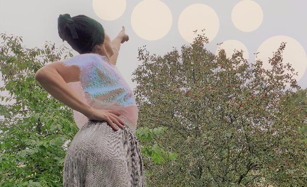 En dansare med rymdig kostym pekar mot den ljusa sommarhimlen med många månar.