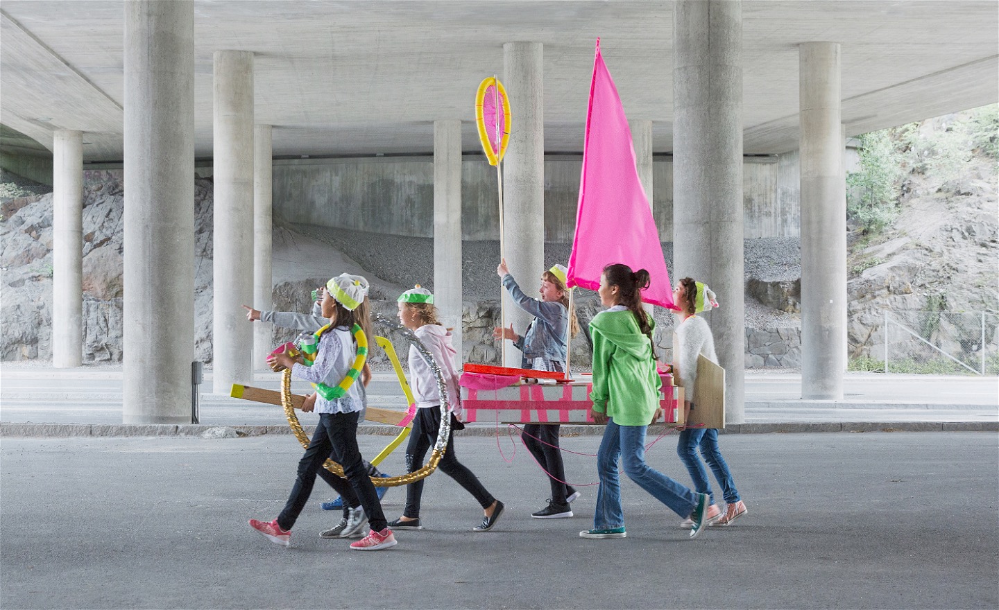  En hembygd båt i neon bärs fram av ett gäng unga tjejer. Med sina egenbyggda farkoster utforskar de ett ingenmansland av betong, där de sätter färg på omgivningen och fyller den med liv och färg.