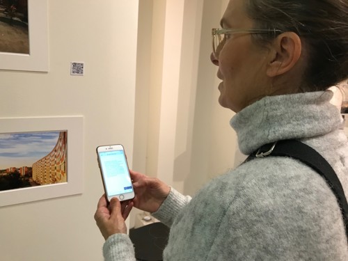 Foto, kvinna tittar på ett foto och läser text från QR-kod i sin mobil