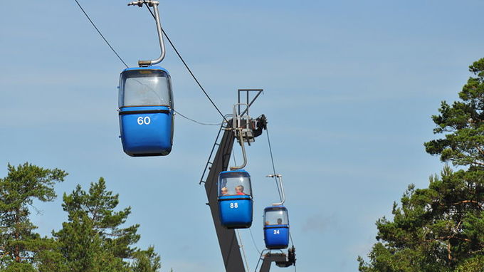 En linbana med tre blåa gondoler.