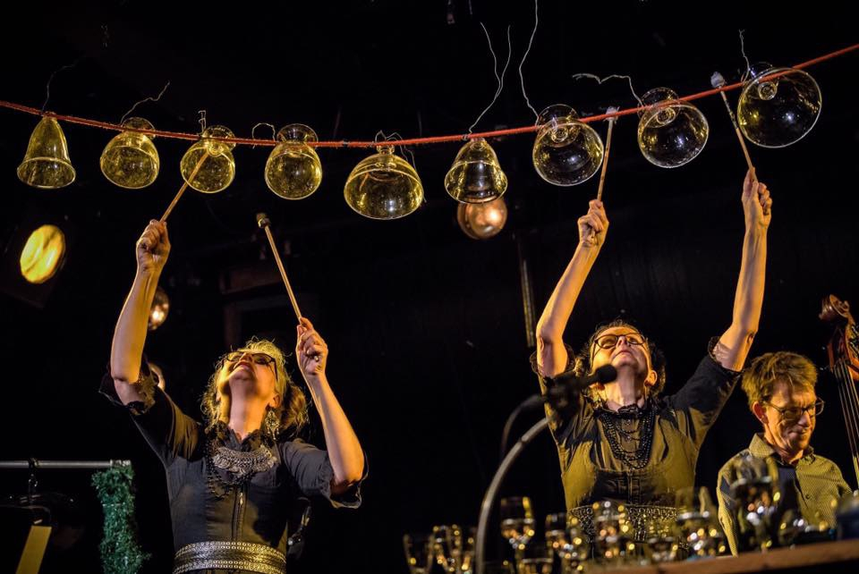 två kvinnor spelar musik med upp och nedvända glas som hänger på en tråd.