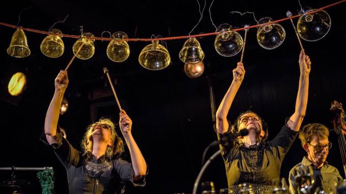 Två kvinnor spelar musik med upp och nedvända glas som hänger på en tråd.
