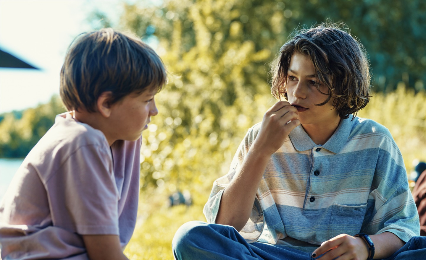 Två pojkar sitter på en grön gräsmatta och ser på varandra. 
