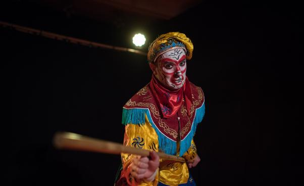 Apkungen håller i en trästav och tittar in i kameran.