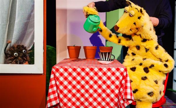 Petra sitter vid bordet och tar en fika medan Pricken tittar ut genom förnstret