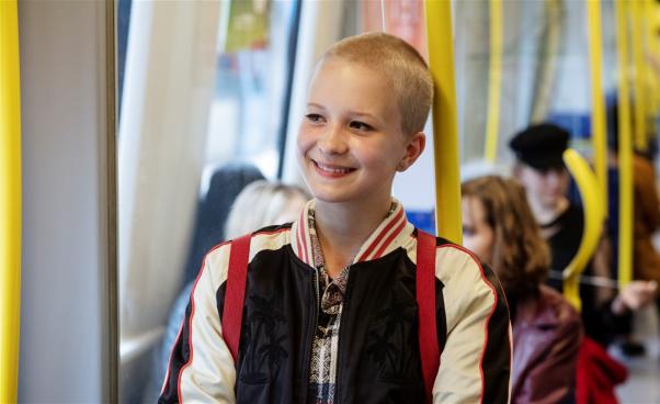 Sasha står i en tunnelbanevagn och ler