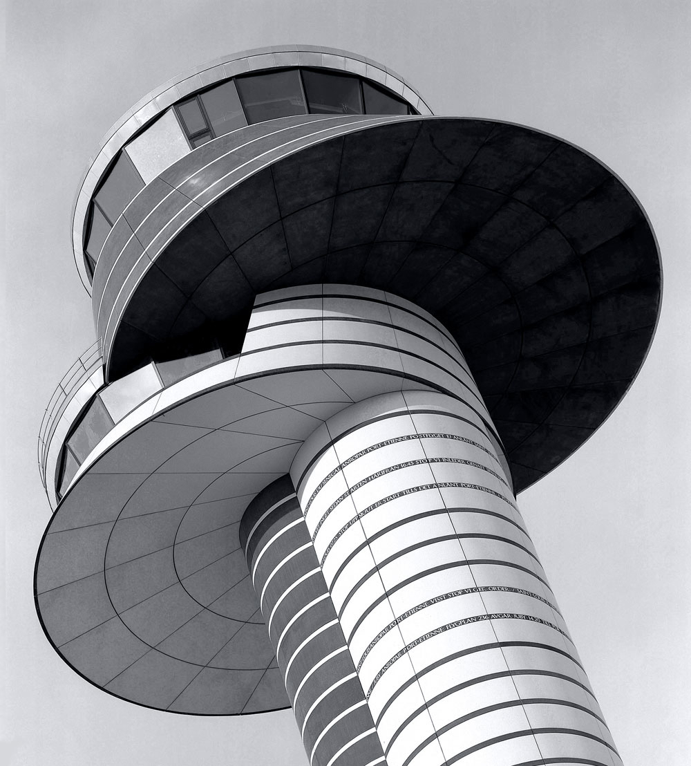 Foto av ett flygledartorn, högst upp på tornet anas hur stiliserade korpar spanar åt olika håll