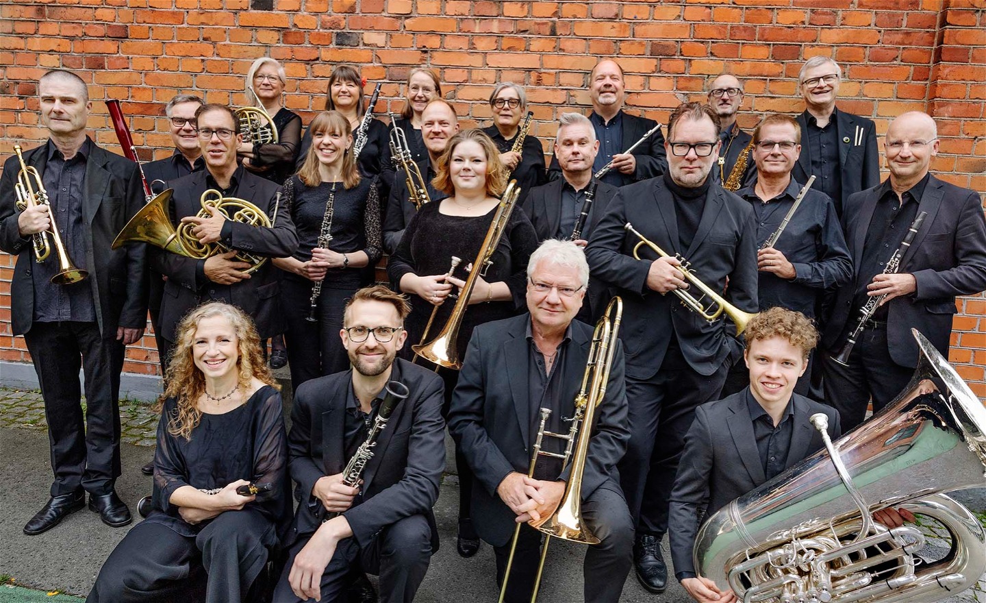 Orkestern Blåsarsymfonikerna i gruppbild utanför Dieselverkstaden i Sickla
