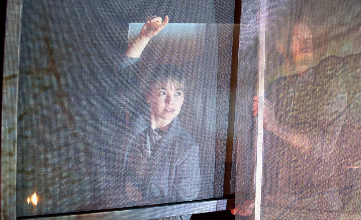 Två dansare bakom nätskärmar med projektioner.