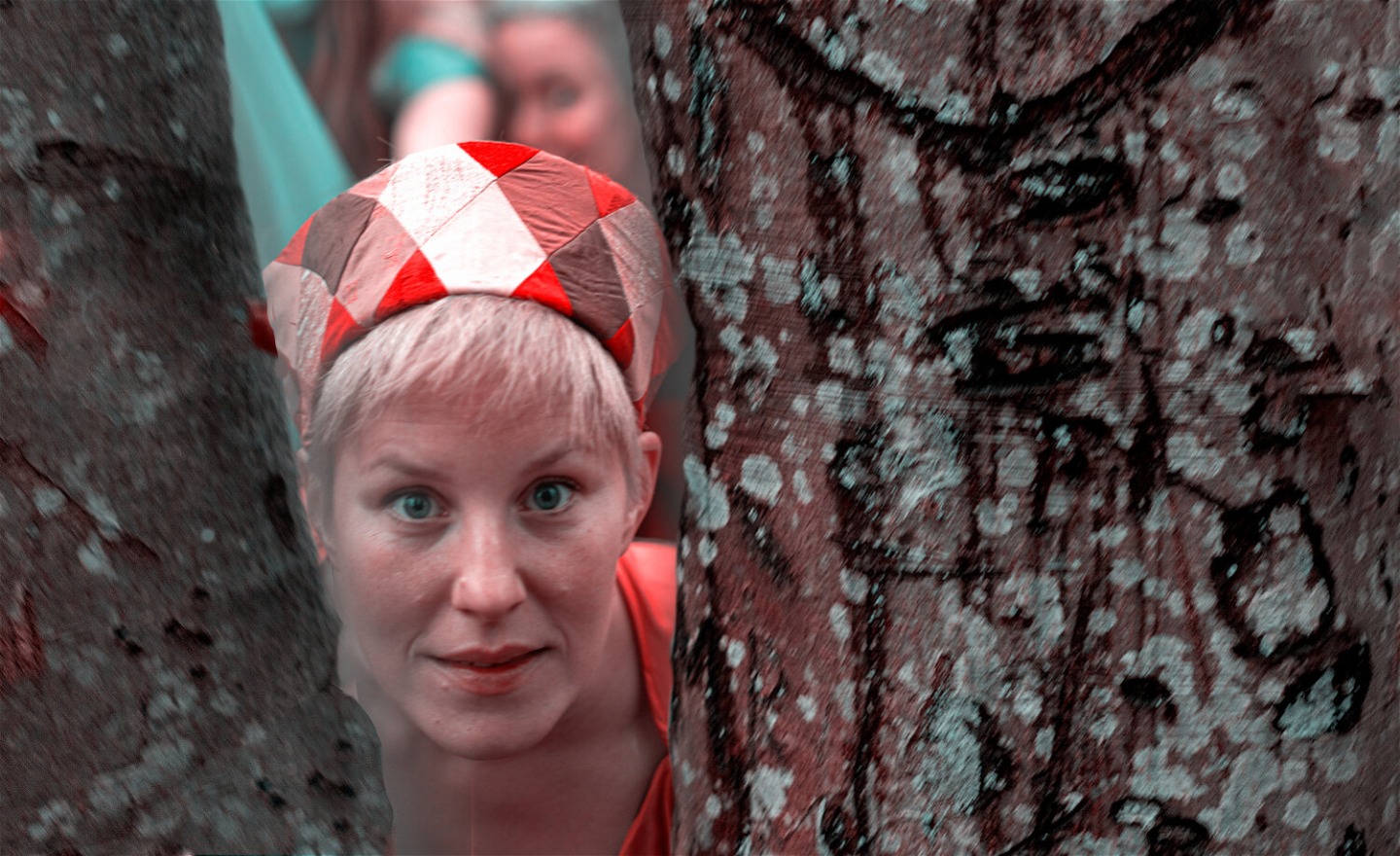 En kvinna tittar fram mellan två träd.