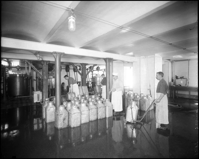 ett gammalt svart vitt fotografi av arbetare i ett mejeri.