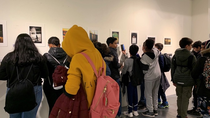 Elever tittar på fotografier på en vägg i en utställningslokal.