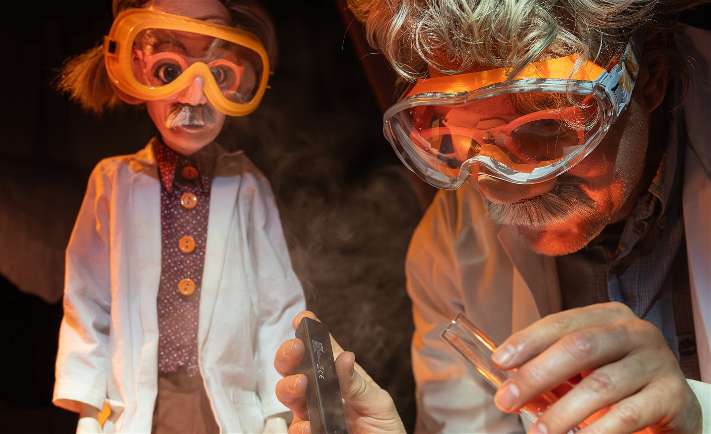 Dockan Albert och Einstein, iförda likadana skyddsglasögon, förbereder ett experiment som ska simulera ett vulkanutbrott.