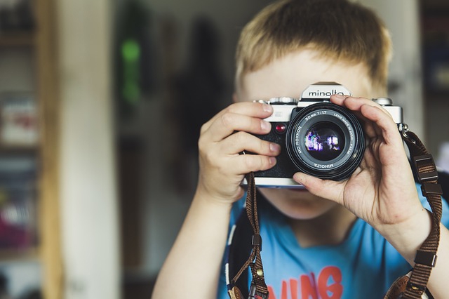 ett barn som håller upp en kamera framför sitt ansikte.