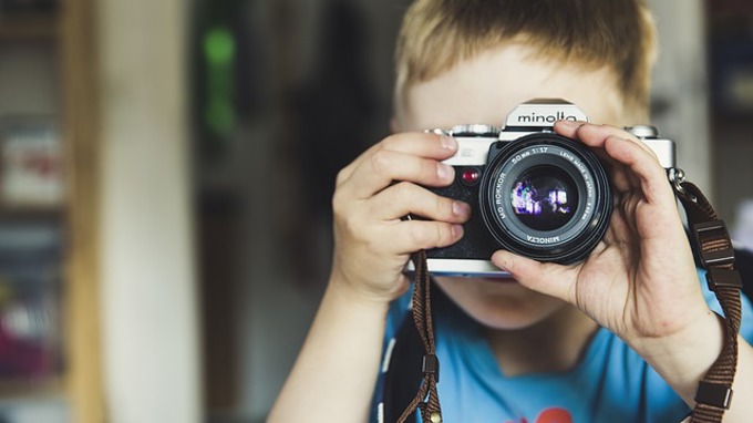 Ett barn som håller upp en kamera framför sitt ansikte.