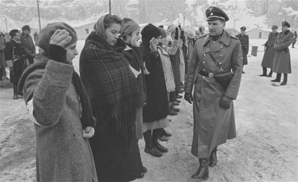 Man i uniform går framför flyktingar