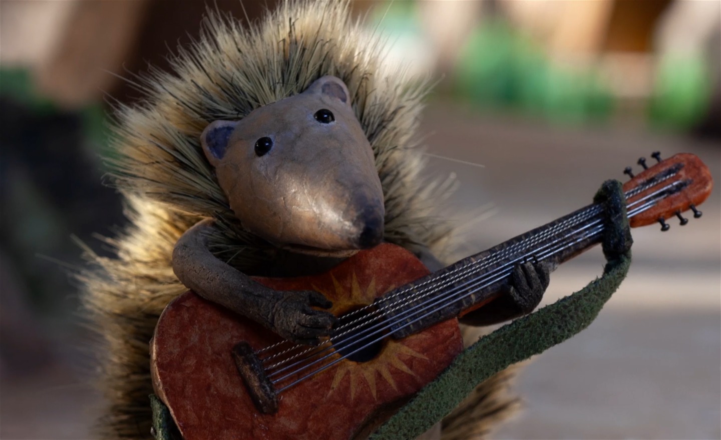 En igelkott håller i en akustisk gitarr.