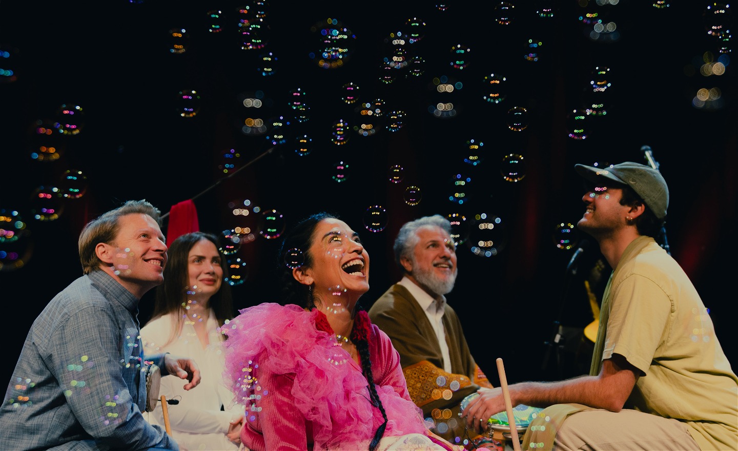 En bild på gruppen Golbangs bandmedlemmar när de sitter på huk och tittar upp mot såpbubblor.