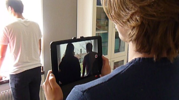 En elev filmar med ipad en annan elev, sett över axeln på filmaren.