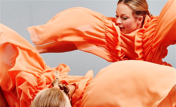 Närbild två dansare i orange flygande dräkter