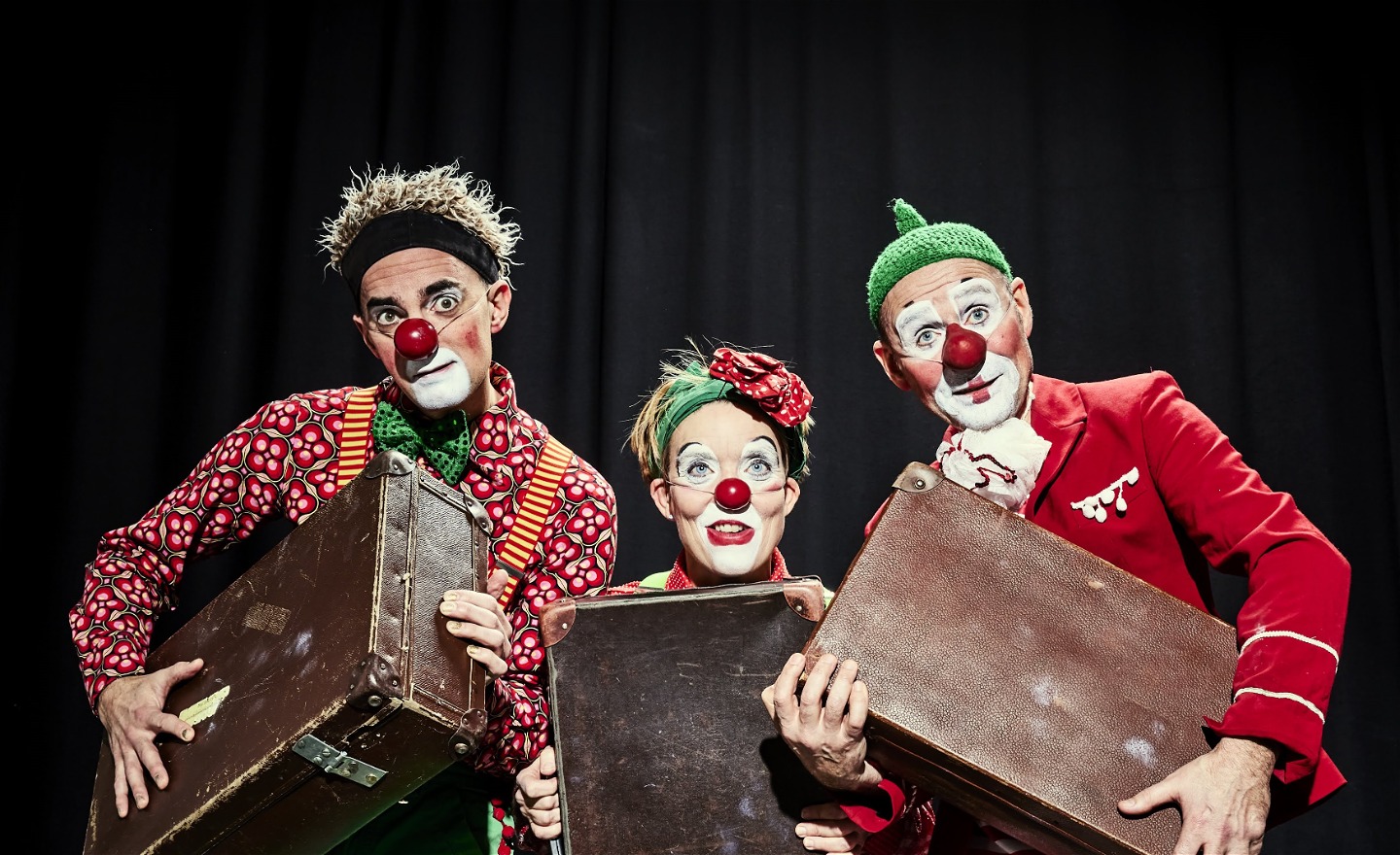Tre glada clowner bär på sina resväskor