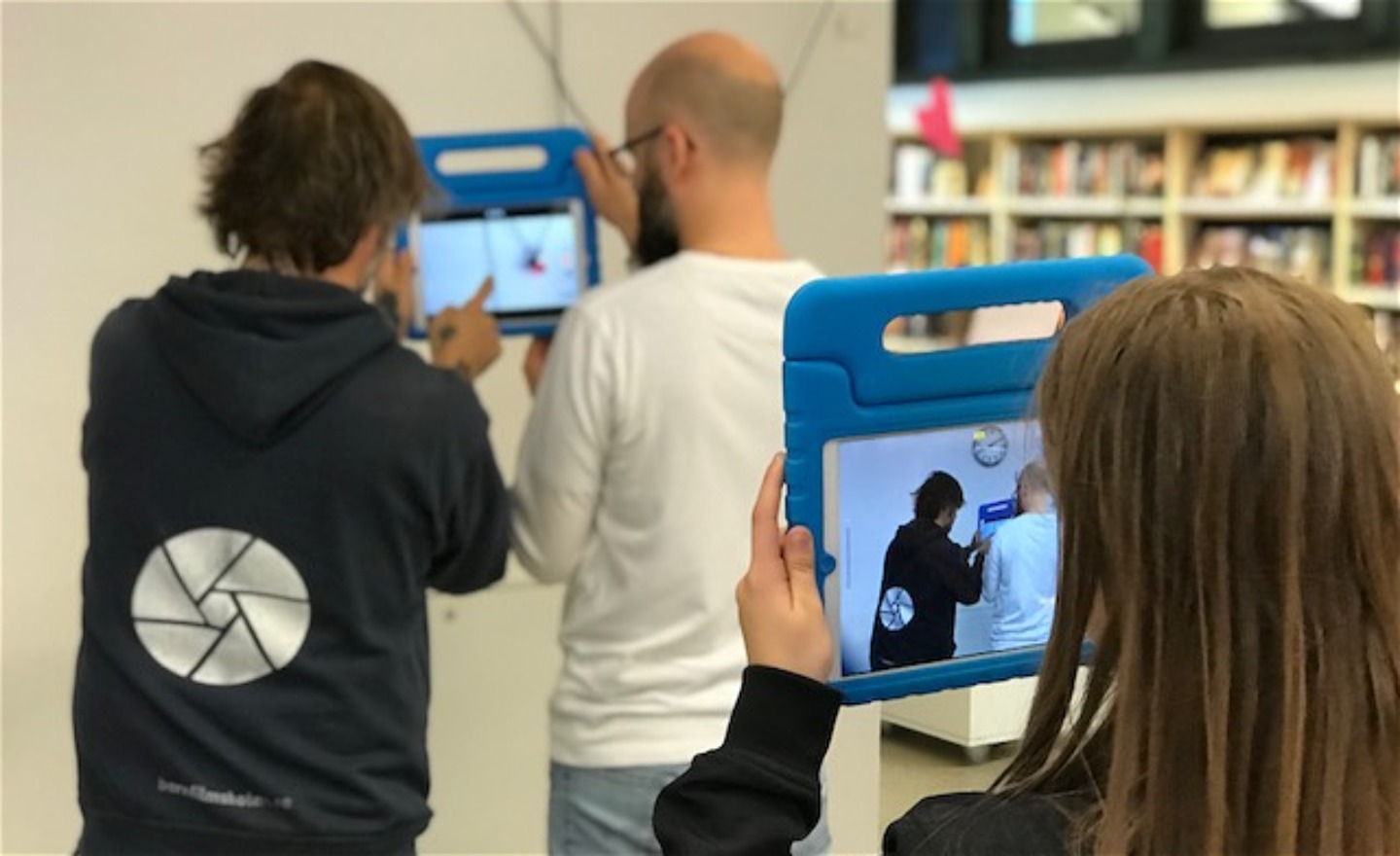 Ett barn filmar två pedagoger som filmar något annat