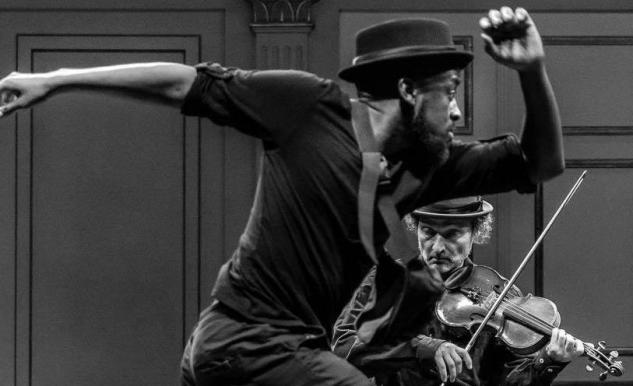 En man dansar och en annan man spelar fiol