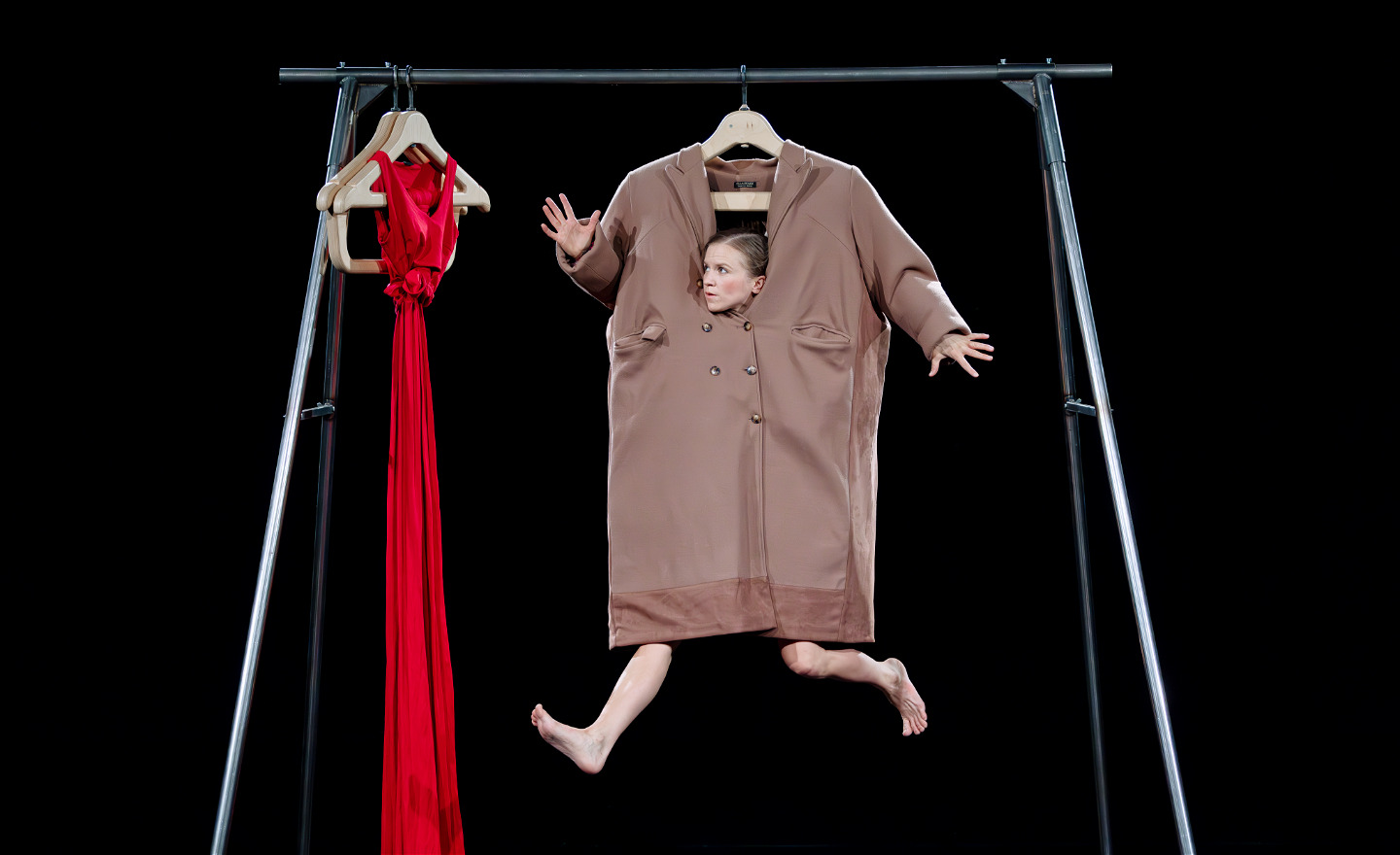 Cirkusartist iklädd en för stor kavaj hänger i en klädställning