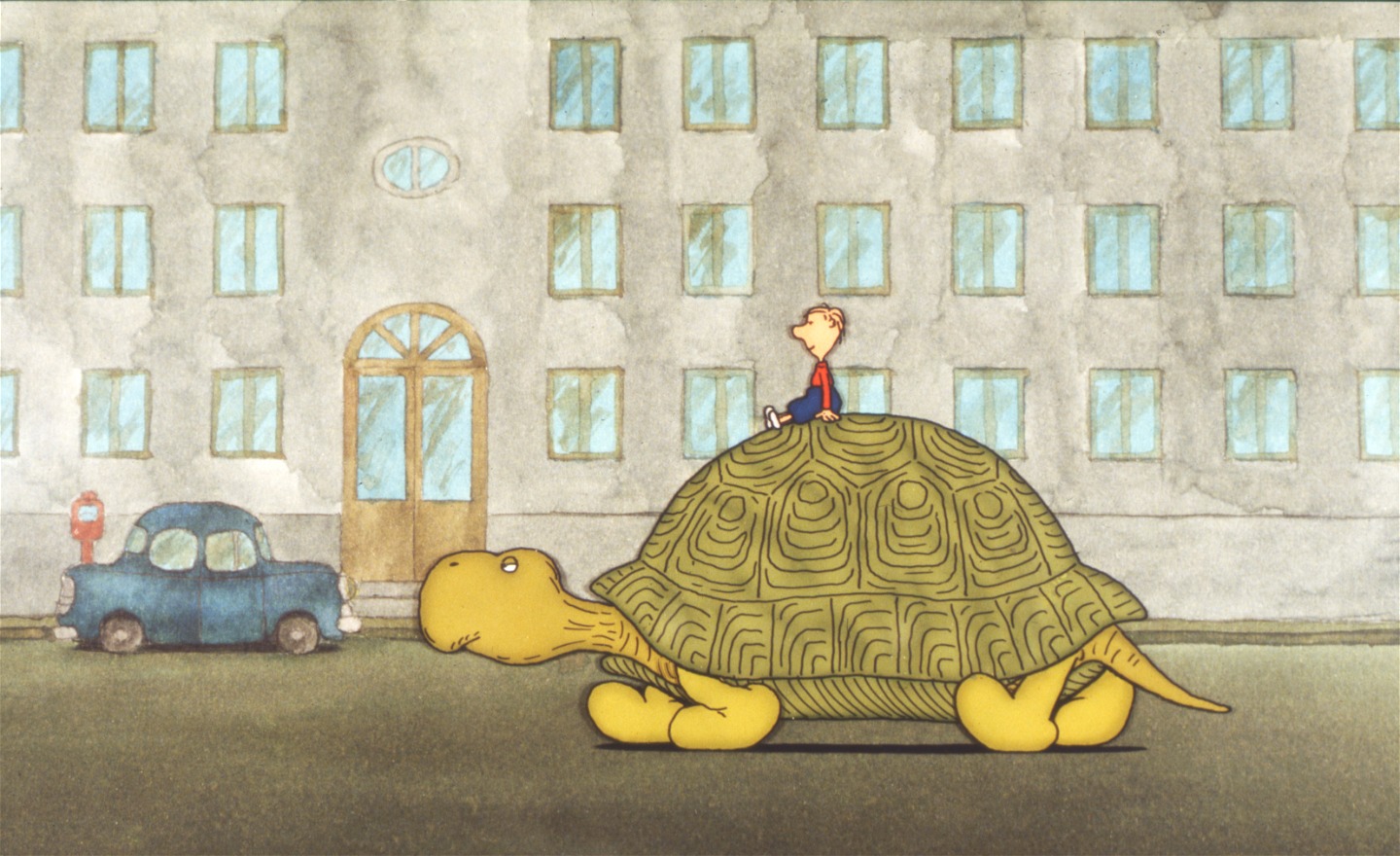 Kalle rider på en stor sköldpadda som går på en stadsgata. I bakgrunden syns ett grått hus med många fönster och en blå bil intill en röd parkeringsautomat.