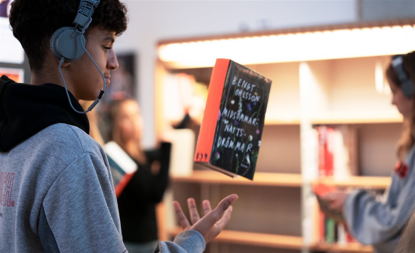 En person med hörlurar kastar upp en bok i luften