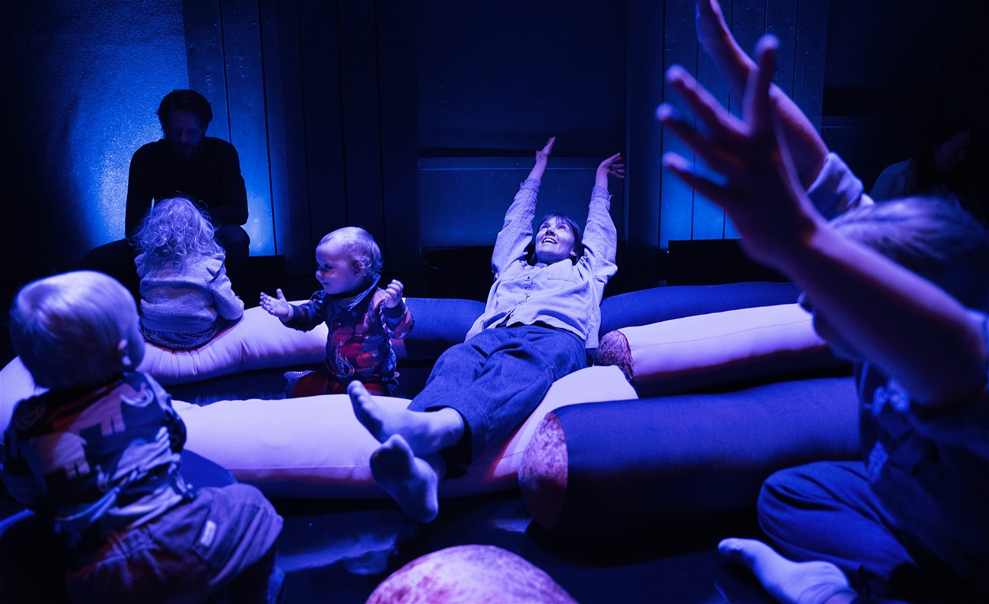 Två dansare och några barn sträcker armarna i luften