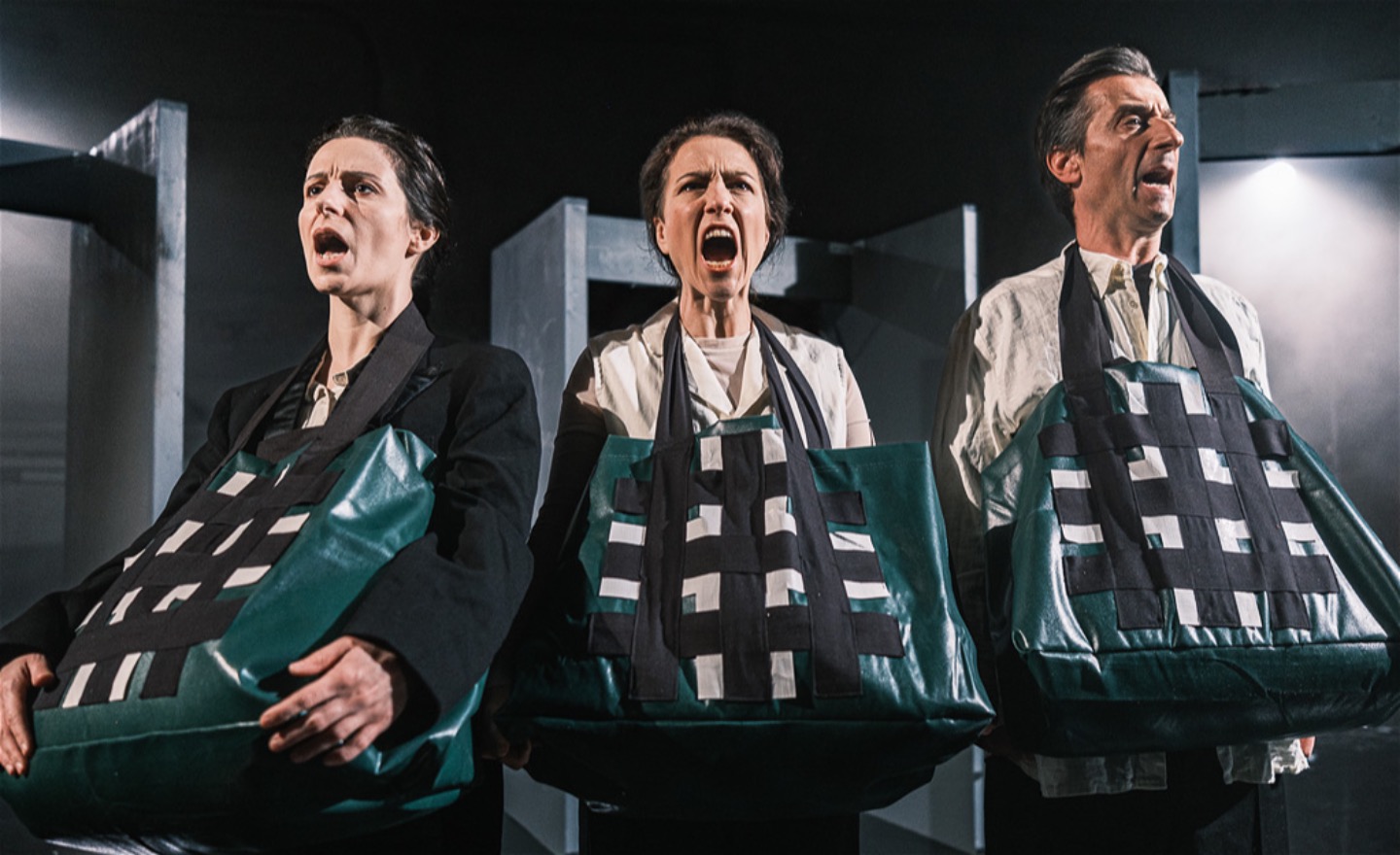 Tre personer står på rad med kassar runt halsarna och skriker.