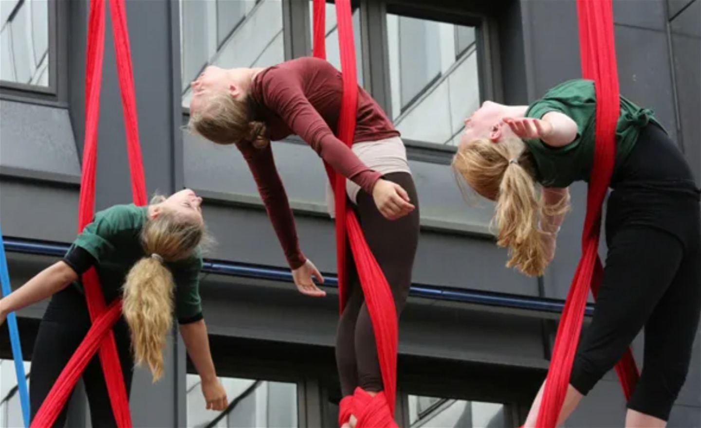 Tre luftakrobater hänger i tyg.