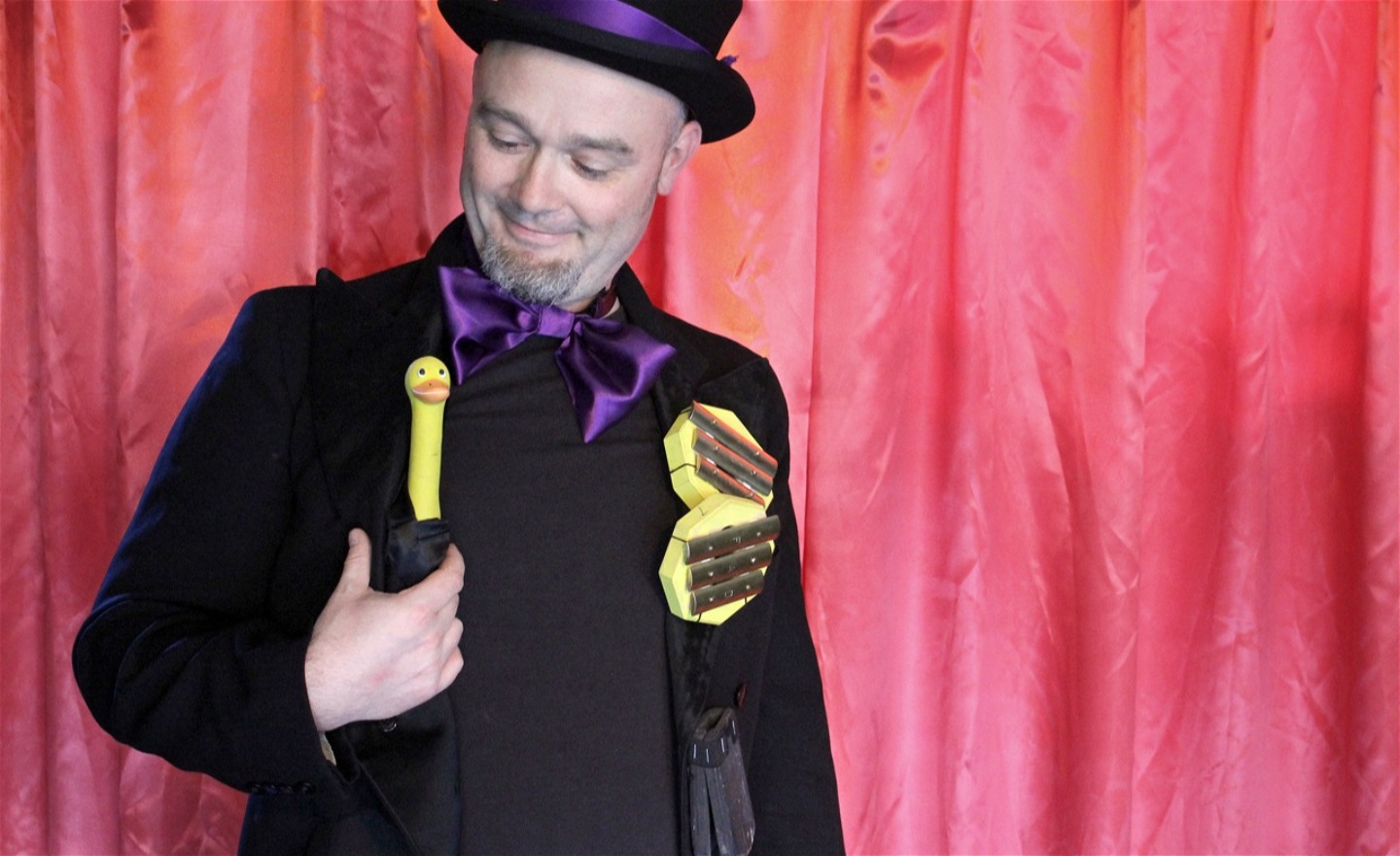 Mikael i frack och hög hatt med en gul pip-anka i handen och klangspelsmedaljer på bröstet