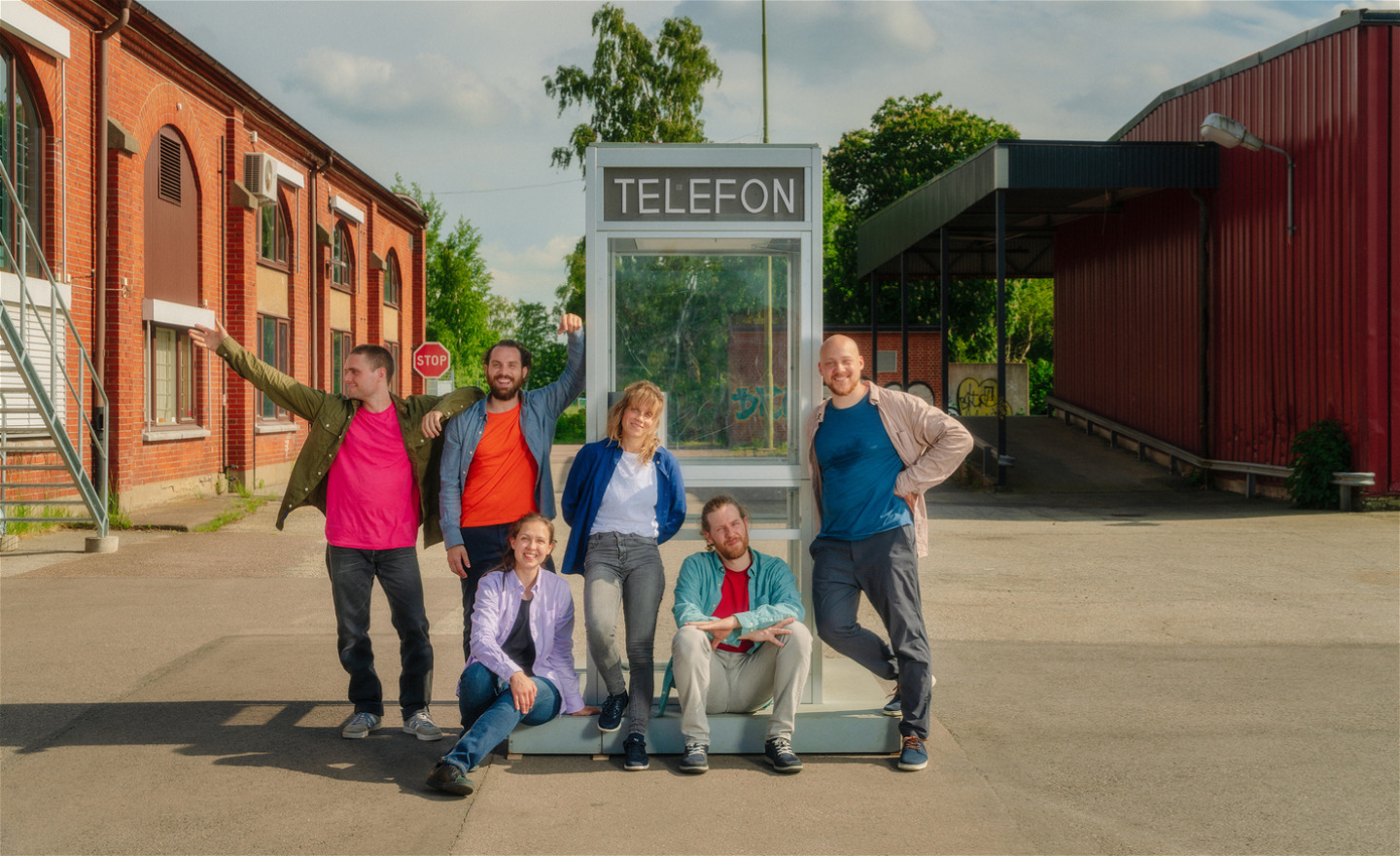 6 personer hänger runt en telefonkiosk