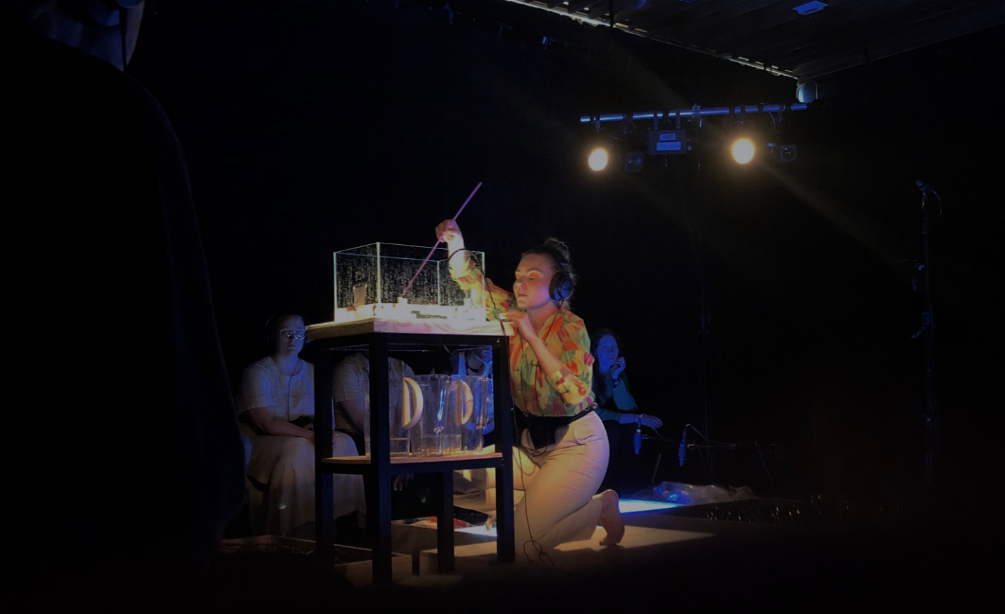 En person sitter framför ett lysande akvarium med hörlurar på sig.