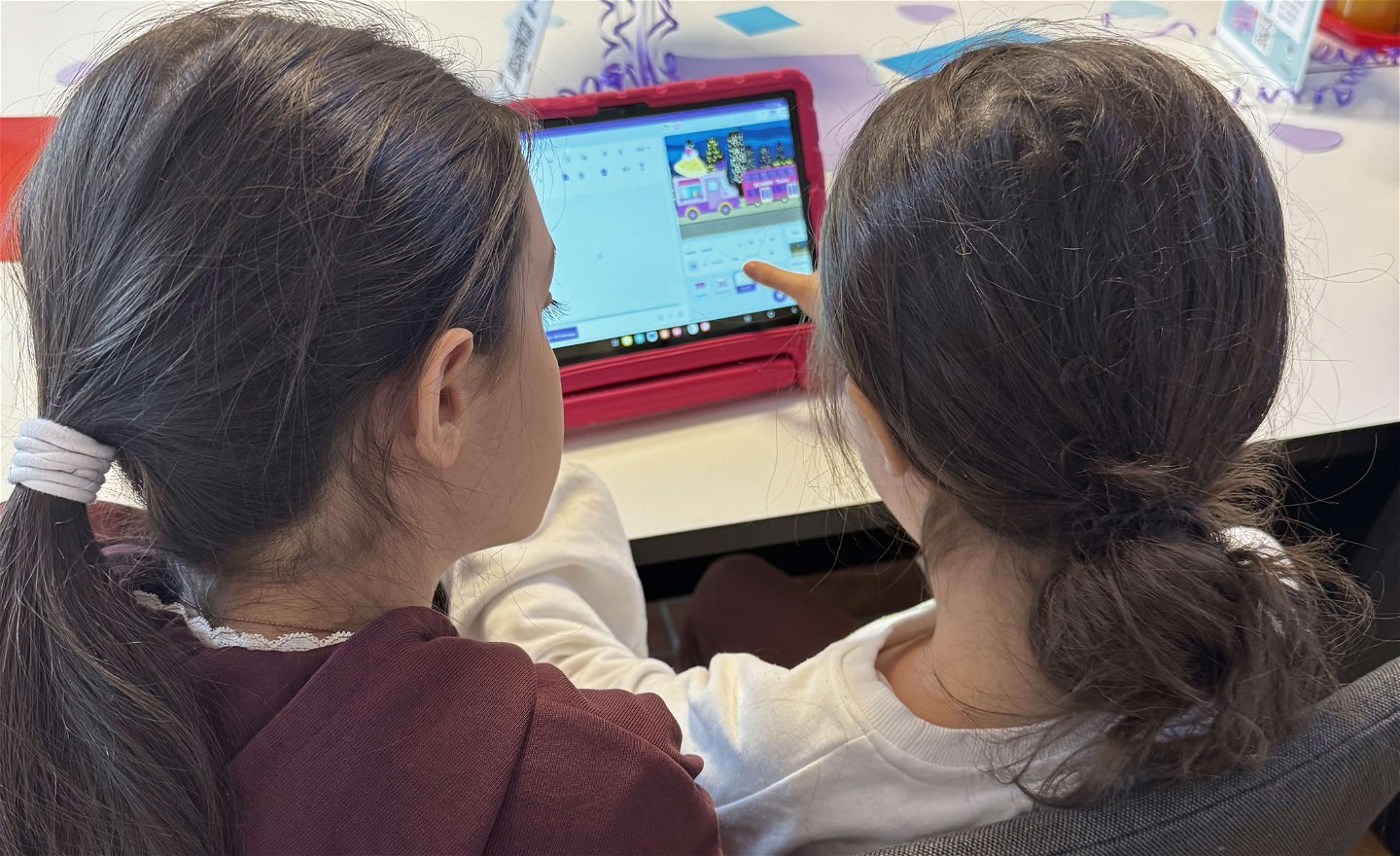 Två barn designar ett eget spel tillsammans på en lärplatta under en Floating Code-workshop.