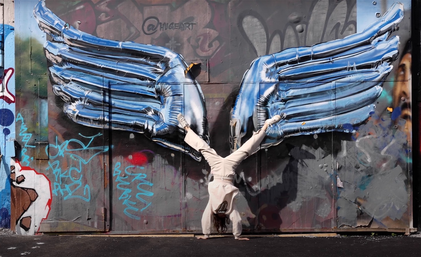 Ett barn som står på händer framför graffitivägg