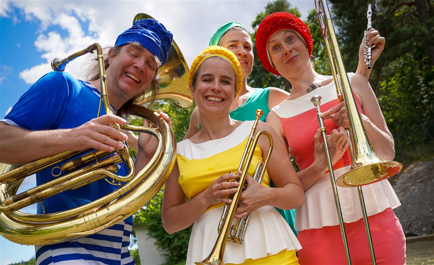fyra blåsmusiker i färgglada baddräkter som ser glada ut