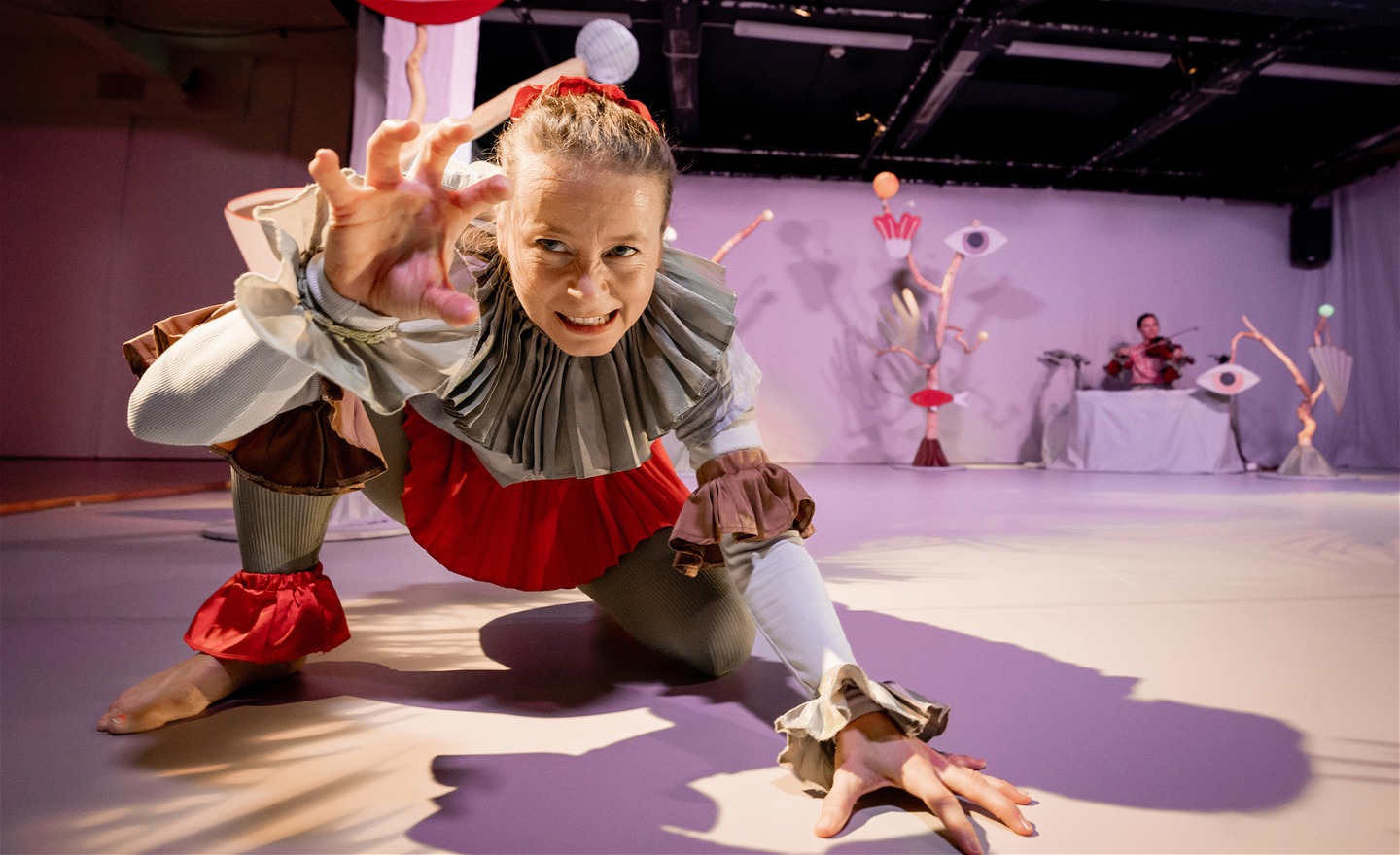 Dansaren Åsa leker att hon är ett lejon, musikern Maja spelar filo i bakgrunden.. 