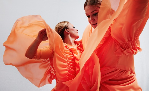 Närbild två dansare i orange flygande dräkter