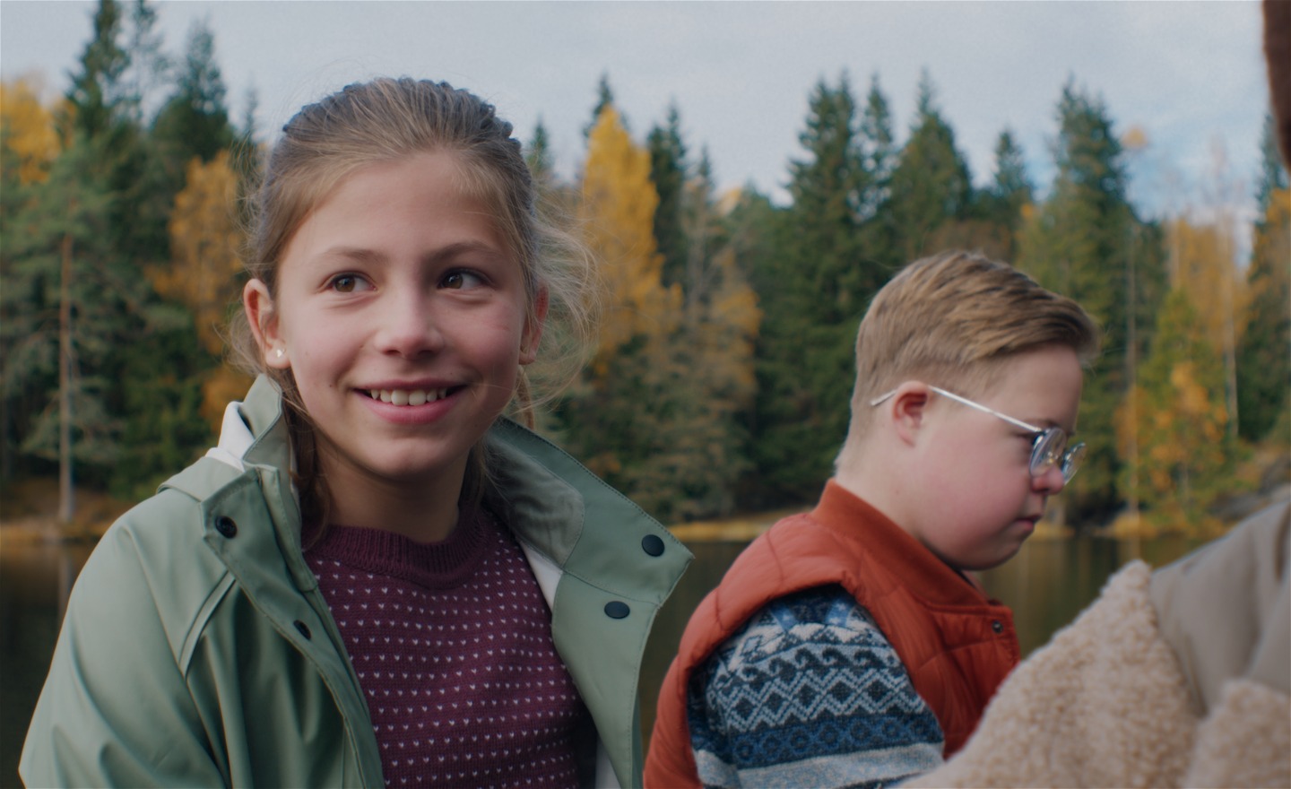 Glad flicka i mellanstadieåldern intill en jämnårig pojke med Downs syndrom som ser allvarlig ut