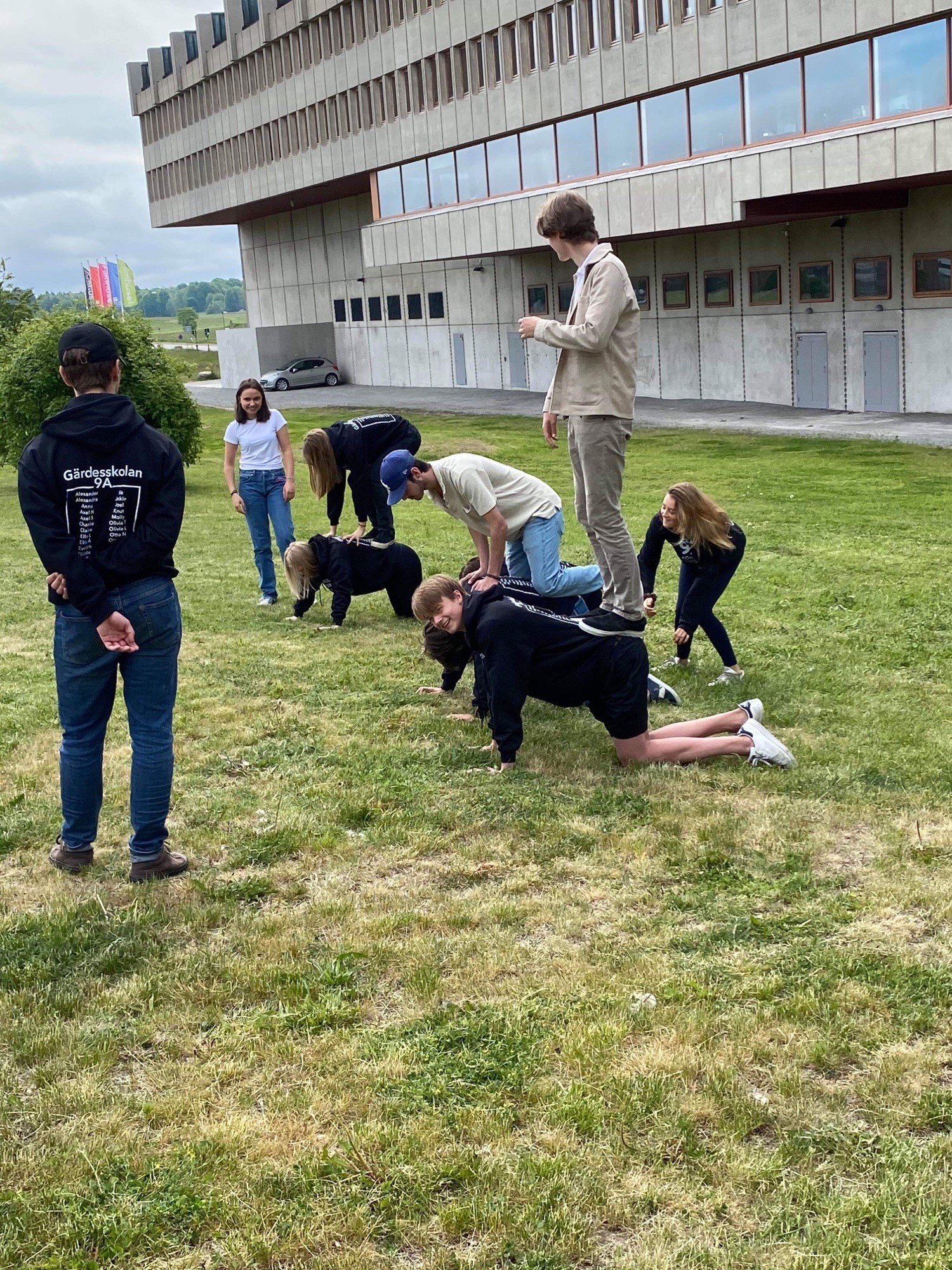 akrobatövningar där elever står på varandras ryggar ute på en gräsmatta.