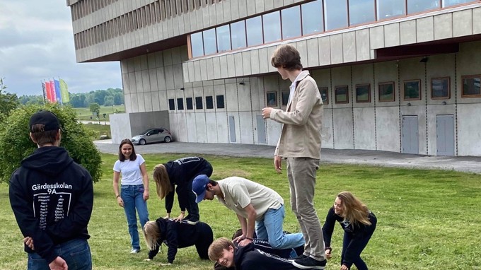 Akrobatövningar där elever står på varandras ryggar ute på en gräsmatta.