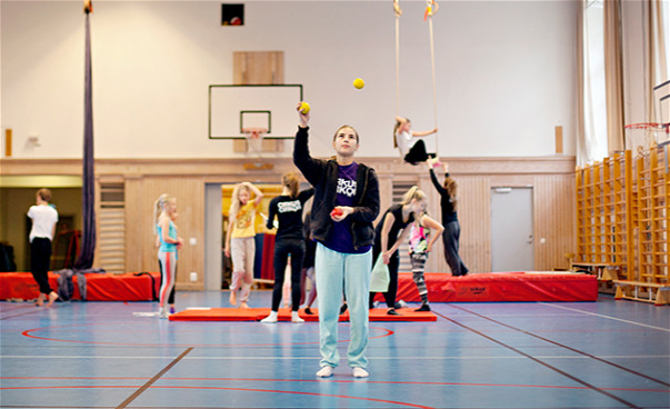 Foto av en ung flicka som tränar jonglering i en gymnastiksal