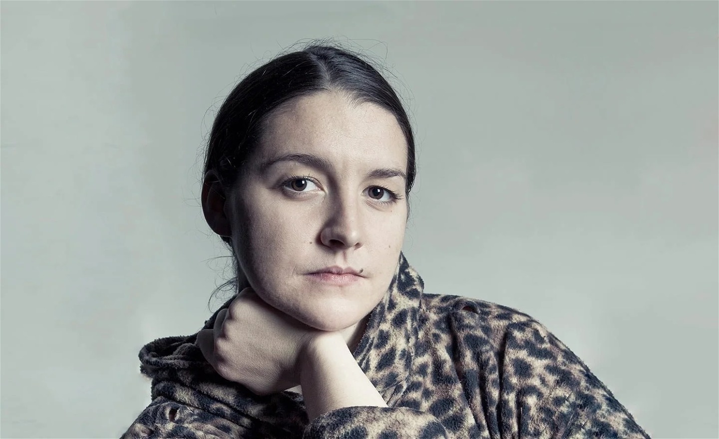 Eleanor Bauer i en leopardmönstrad hoodie lutar huvudet mot ena handen med en avslappnad blick mot kameran